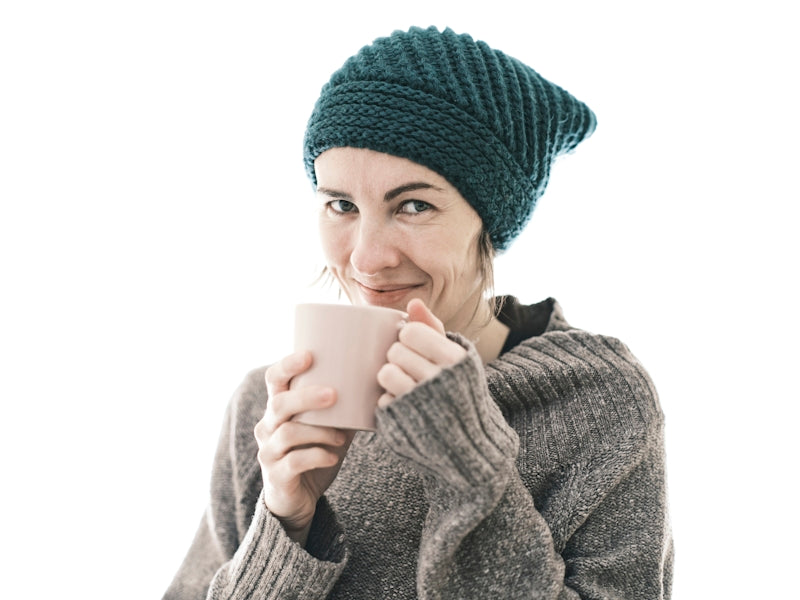 a woman wearing a knitted hat and holding a cup