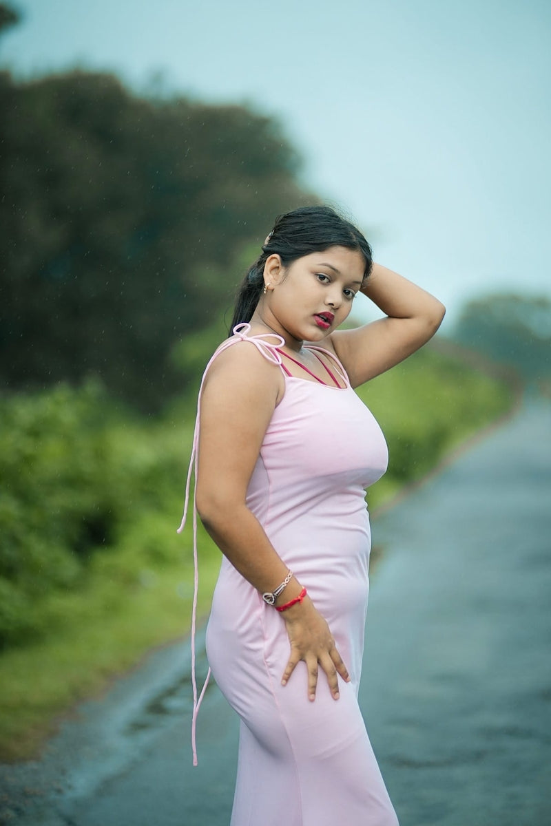 A woman in a pink dress standing on the side of a road